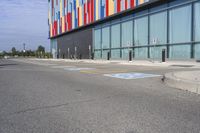 a picture of the street outside a multi - color building with markings on it's parking spaces