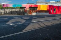 colorful building with tree shadow at the corner on the side of the road while cars are passing by