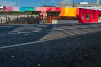 colorful building with tree shadow at the corner on the side of the road while cars are passing by