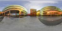 three colorful buildings on a round surface by a skateboarder in motion at the edge of a ramp