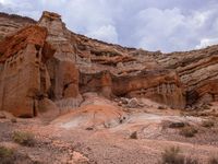 the large cliffs are colorful in the desert land below the clouds and sky, but have no shadow