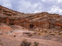 the large cliffs are colorful in the desert land below the clouds and sky, but have no shadow