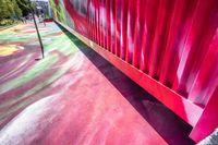 colorful floor paint with a green red yellow orange and pink pattern near a gate to a playground