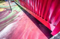 colorful floor paint with a green red yellow orange and pink pattern near a gate to a playground