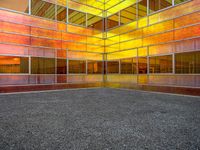 colorful photograph of a large glass building surrounded by parking lot and windows with no glass