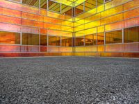 colorful photograph of a large glass building surrounded by parking lot and windows with no glass