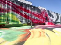 a multi - colored graffiti painting covering an old train car on tracks near a sidewalk