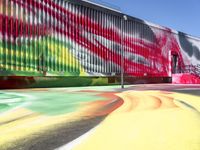 a multi - colored graffiti painting covering an old train car on tracks near a sidewalk