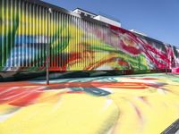 a multi - colored graffiti painting covering an old train car on tracks near a sidewalk