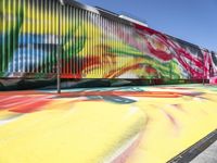 a multi - colored graffiti painting covering an old train car on tracks near a sidewalk