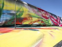 a multi - colored graffiti painting covering an old train car on tracks near a sidewalk