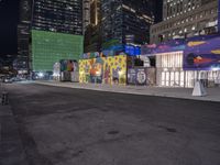 a colorful graffiti covered building with a big moon at night and some buildings all around it