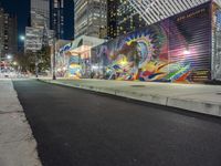 a colorful graffiti mural on a side walk of a building near a sidewalk and street light