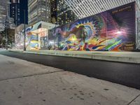 a colorful graffiti mural on a side walk of a building near a sidewalk and street light