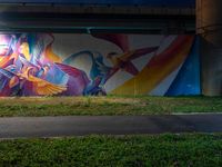 a colorful painted mural next to the street light at night in a building underpass