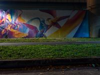 a colorful painted mural next to the street light at night in a building underpass