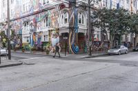 a city street with graffiti covering a colorful building and trees in front of it while parked cars sit nearby the stoplight