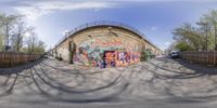 a very wide view of a street through a fisheye lens lens to show a colorful graffiti wall