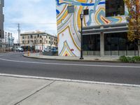 there is a colorful wall painted on the side of a building near a city street