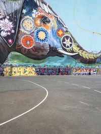 an elephant in front of a colorful mural on the side of a building with a flying kite