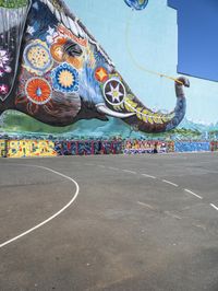 an elephant in front of a colorful mural on the side of a building with a flying kite