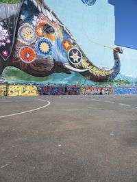 an elephant in front of a colorful mural on the side of a building with a flying kite