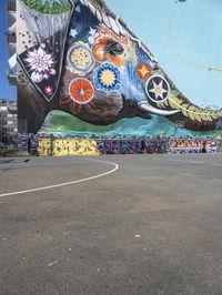 an elephant in front of a colorful mural on the side of a building with a flying kite