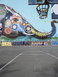 an elephant in front of a colorful mural on the side of a building with a flying kite