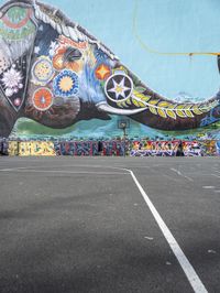 an elephant in front of a colorful mural on the side of a building with a flying kite