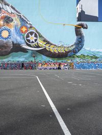 an elephant in front of a colorful mural on the side of a building with a flying kite