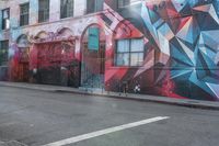 a colorful mural is on the side of an alleyway near a red fire hydrant