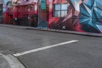 a colorful mural is on the side of an alleyway near a red fire hydrant