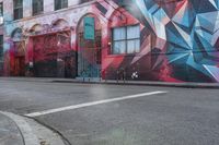 a colorful mural is on the side of an alleyway near a red fire hydrant