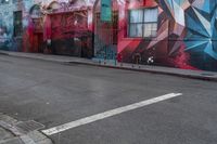 a colorful mural is on the side of an alleyway near a red fire hydrant