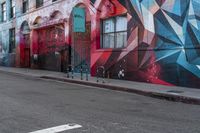 a colorful mural is on the side of an alleyway near a red fire hydrant