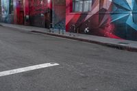 a colorful mural is on the side of an alleyway near a red fire hydrant