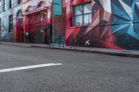 a colorful mural is on the side of an alleyway near a red fire hydrant