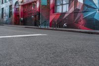 a colorful mural is on the side of an alleyway near a red fire hydrant