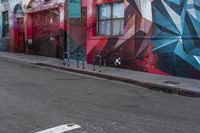 a colorful mural is on the side of an alleyway near a red fire hydrant