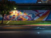 a street light in front of a colorful mural on the wall of an underpass