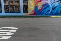 a colorful mural with a woman's face and bird painted on it along a street