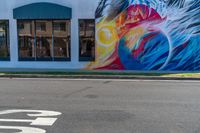 a colorful mural with a woman's face and bird painted on it along a street