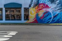 a colorful mural with a woman's face and bird painted on it along a street