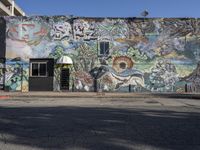 an exterior shot of a colorful mural wall with trees, flowers and plants painted on it