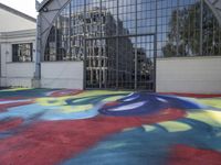 a large colorful patch of paint is placed on the floor of an industrial building near an arch