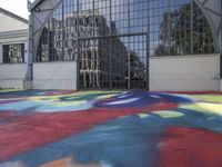 a large colorful patch of paint is placed on the floor of an industrial building near an arch