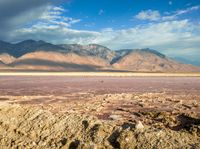 the desert is covered in red, orange and purple water as a person stands by