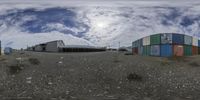 three colorful shipping containers in front of a sky with white clouds overhead as they are parked