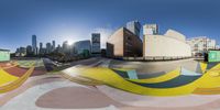 a half - pipe skateboard park with an artistic design on it in front of city buildings