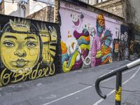 a colorful wall has been painted by various people on it's side, with two street railings